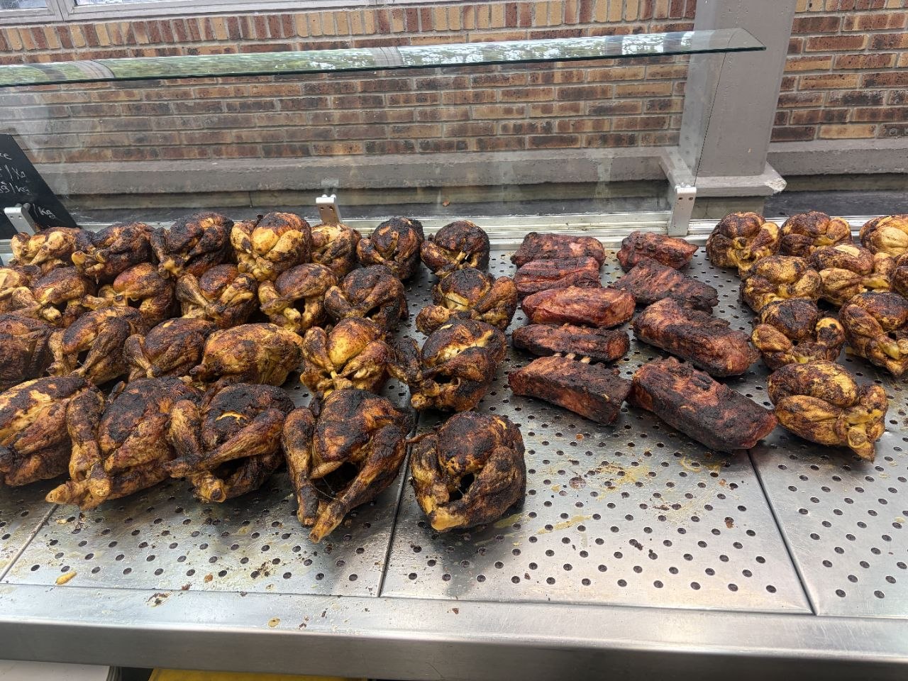 L'étal de Chez Dave : poulets rôtis, travers de porc et cuisses sous la vitre du stand.